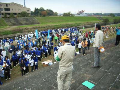 土手階段の上から河川敷の大勢の参加者に開会の挨拶